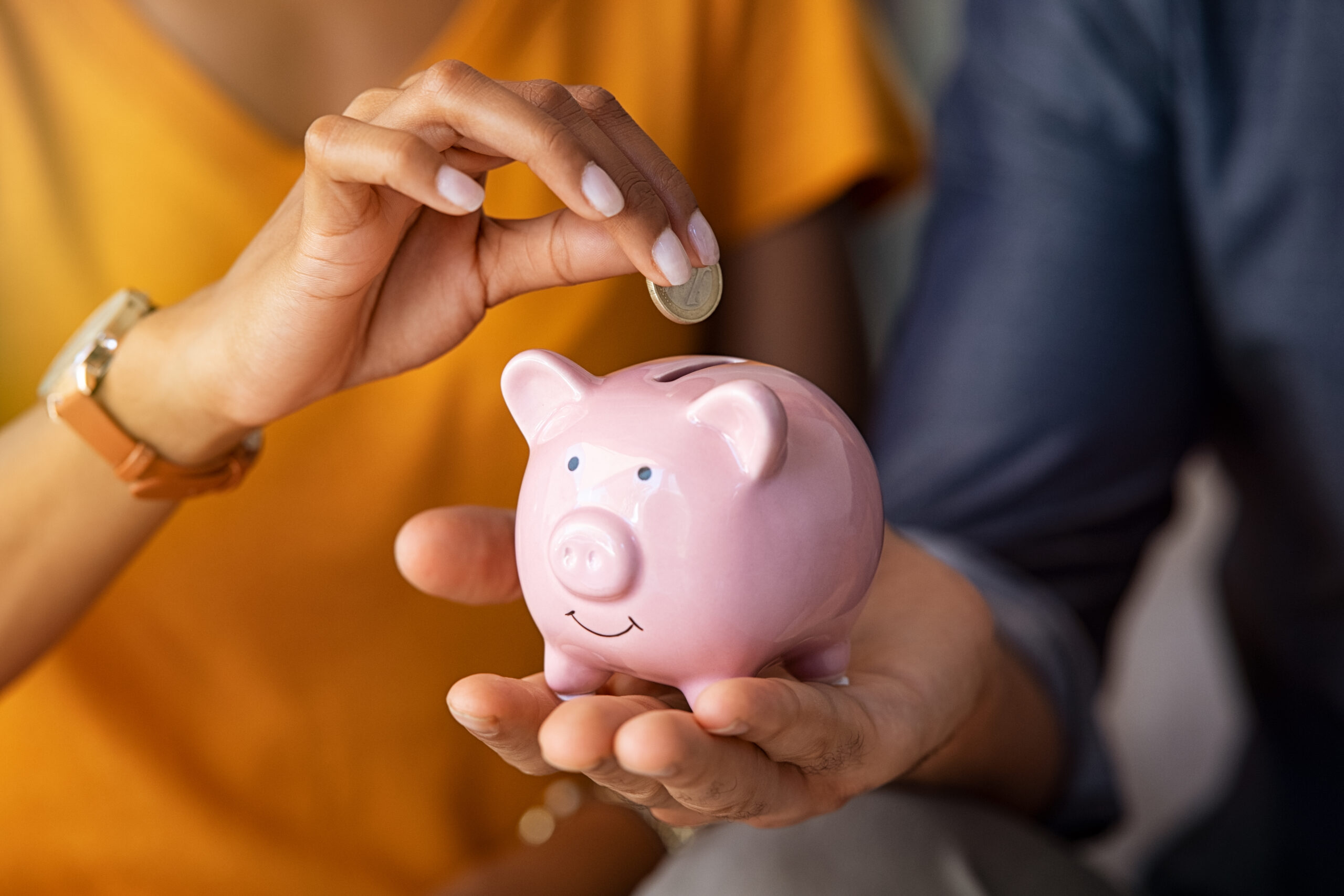 Close,Up,Of,Man,Holding,Pink,Piggybank,While,Woman,Putting