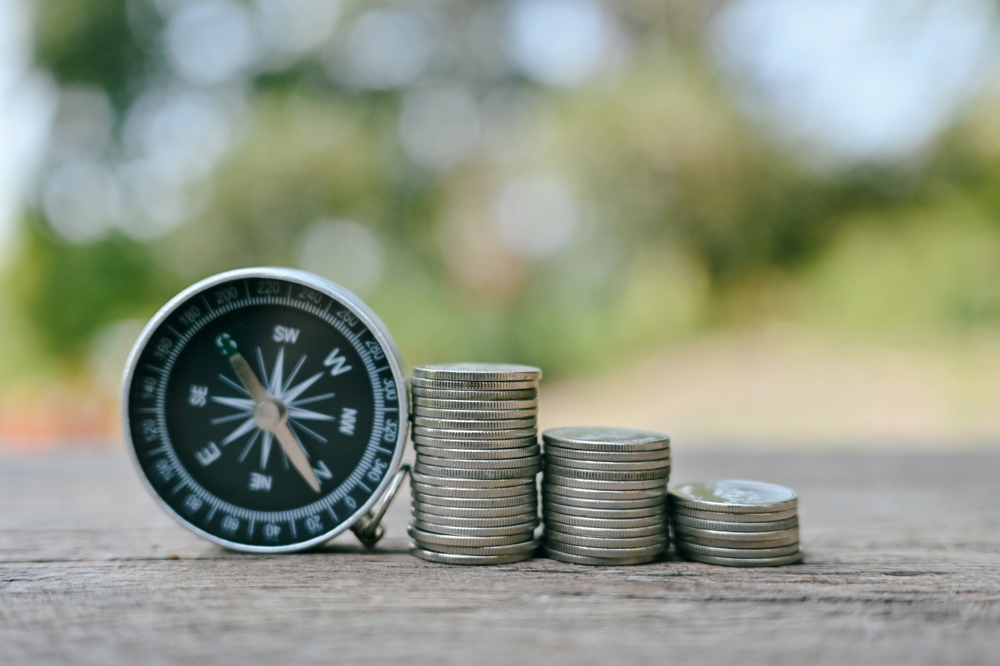 Close,Up,Stack,Of,Coin,And,Compass,On,Table,,Planning