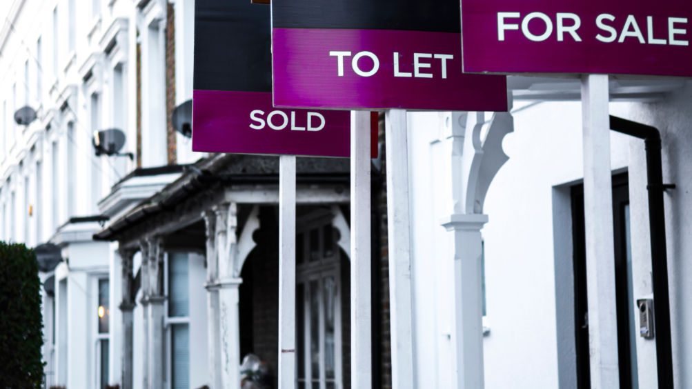 Estate agent  'for sale', 'to let' and 'sold' signage boards of street of terraced houses